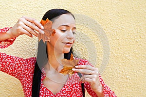 Portrait of young, natural and healthy woman over yellow autumn background with orange leaves