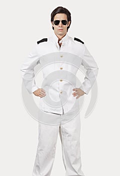Portrait of young navy officer standing against gray background