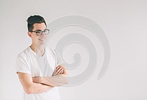 Portrait of young Nerd man wearing glasses and t-shirt standing with crossed arms and smiling isolated on white