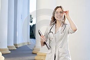 Portrait of a young nurse, medical university student girl stands with phonendoscope and documents, happy female doctor in uniform