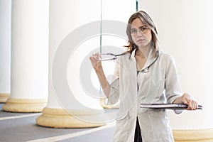 Portrait of a young nurse, medical university student girl stands with phonendoscope and documents, happy female doctor in uniform