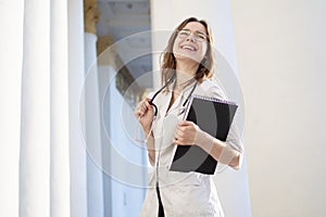 Portrait of a young nurse, medical university student girl stands with phonendoscope and documents, happy female doctor in uniform