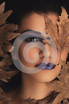 Portrait of young oman over autumn background. Healthcare, makeup and face lifting concept.