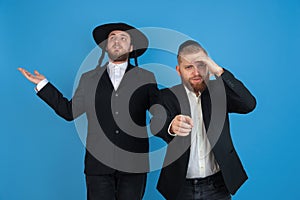 Portrait of a young orthodox jewish men  on blue studio background, meeting the Passover, astonished