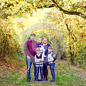 Portrait of young parents with three children. Mother, father, two kids brothers boys and little cute toddler sister