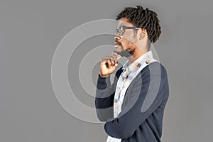 portrait of young pensive african american man posing in glasses wearing jumper touching chin looking sideways, isolated