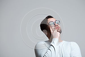 Portrait of young pensive man wearing blue glasses over white background