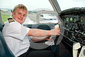 Portrait of young pilot with down syndrome in cabin.