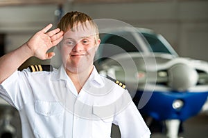 Portrait of young pilot with down syndrome in hangar. photo