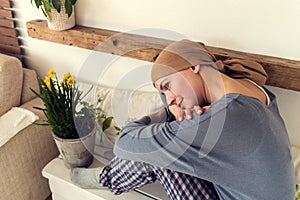 Portrait of young positive adult female cancer patient sitting in living room in her pajamas.