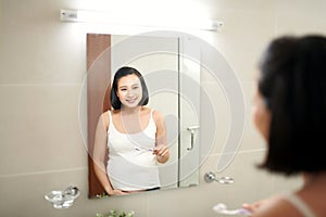 Portrait of young pregnant woman brushing teeth at bathroom