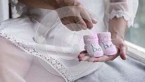 Portrait of the young pregnant woman. Pregnancy, love, people and expectation concept. Close up of a pink baby`s booties