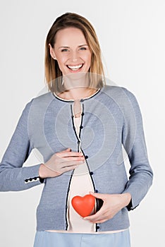 portrait of young pregnant woman with red heart in studio
