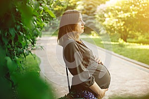 Portrait of young pregnant woman walking in a park