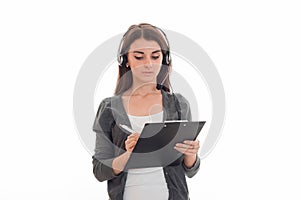 Portrait of young pretty call center worker girl with headphones and microphone makes notes isolated on white background