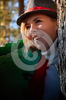 Portrait of young pretty funny smiling girl in male hat in sunny autumn day. Young happy woman having fun outdoor