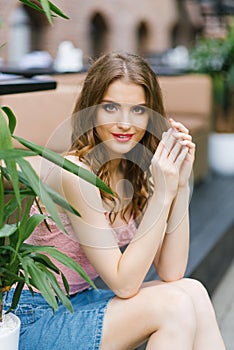 Portrait of a young pretty girl with bright expressive eyes and professional makeup. The girl holds her hands to her face.