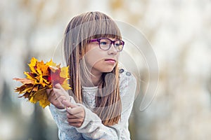 Portrait of a young pretty girl who was cheerfully playing with autumn maple leaves.Girl sitting on colorful autumn leaves.