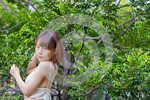 Portrait of young pretty sexy Asian woman wearing bikini in garden