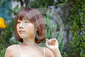 Portrait of young pretty sexy Asian woman wearing bikini in garden