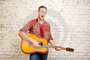 Portrait of young pretty singer playing on the guitar