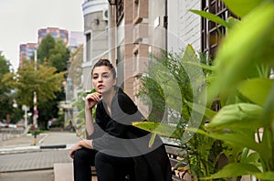 Portrait of young pretty student woman sitting at the city openspace