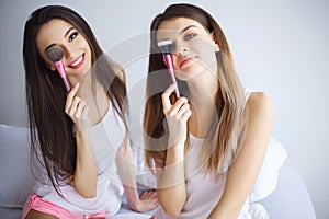 Portrait of young pretty woman doing maquillage to her sister