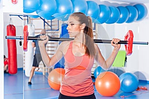 Portrait of a young pretty woman holding crossfit barbell and doing fitness indor. Crossfit hall. Gym shot.