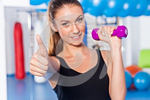 Portrait of a young pretty woman holding weights (dumbbell) and