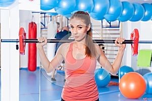 Portrait of a young pretty woman holding weights (dumbbell) and doing fitness indor. Crossfit hall. Gym shot.