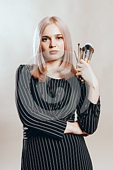 Portrait of a young pretty woman with make-up brushes