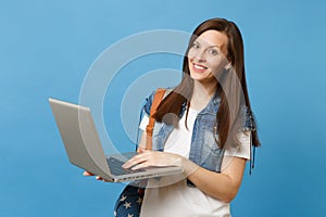 Portrait of young pretty woman student in denim clothes with backpack holding and using working on laptop pc computer