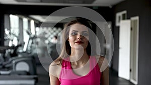 Portrait of Young pretty woman training with dumbbells sitting on a bench in gym. Heathy lifestyle, sport conception