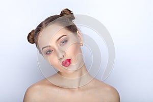 Portrait of a young pretty woman with trendy makeup bright red lips funny bun hairstyle and bare shoulders act the ape against