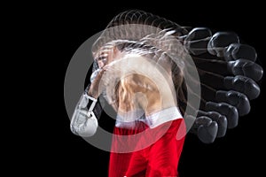 Portrait of young professional male boxer in red shorts and boxing gloves training, exercising over black studio