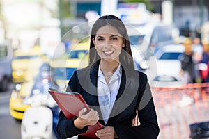 Portrait of a young, professional woman in business clothing holding a filecase