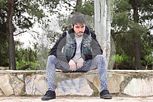 Portrait of a young punk man wearing leopard leggins, black hoody and denim vest