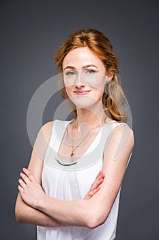 Portrait of a young redhaired beautiful girl in the studio on a gray isolated background. A woman is standing with her