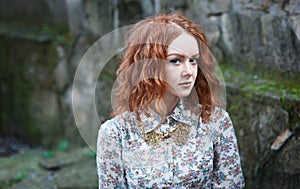 Portrait of a young red-haired curly girl with freckles in a vintage necklace