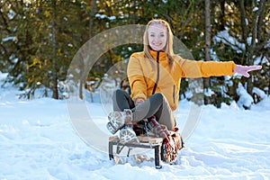 Portrait of young red-haired woman in an orange jacket in snowy forest. Fiery-haired girl has fun in woods