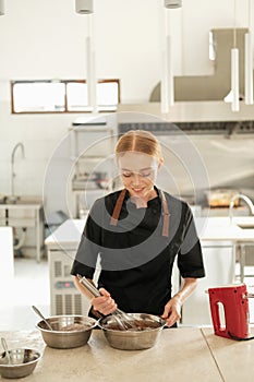 Portrait of a young red haired woman pastry chef who kneads chocolate dough