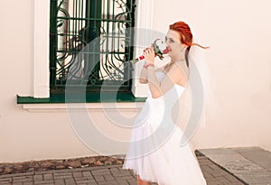 Portrait of young redhead bride with bouquet of roses.
