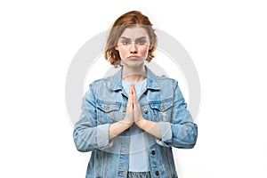 Portrait of young redhead woman folded her hands in prayer gesture isolated on white background. Peaceful, grateful, trusting