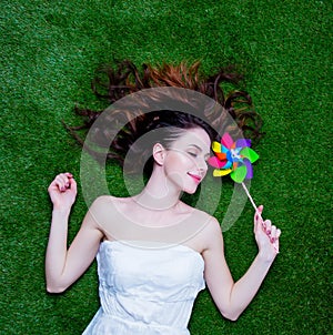 Portrait of a young redhead woman with pinwheel lying down on gr
