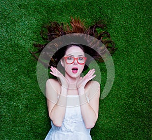 Portrait of a young redhead woman with styled glasses lying down