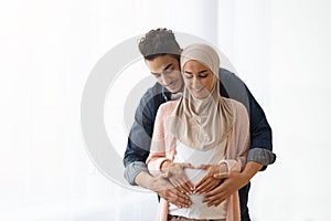 Portrait of young religious muslim couple expecting baby bonding at home