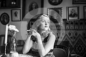 Portrait of a young retro lady sitting at a vintage cafe.