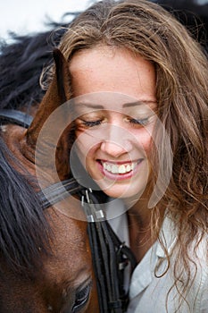 Portrait of young rider woman with her bay horse