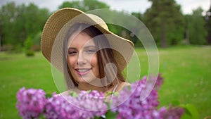 Portrait of young romantic smiling beautiful girl sniffing smelling lilac flowers in bouquet in nature forest