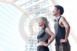 Portrait of young runner man and woman standing with arms akimbo outside, resting after exercise run outdoor, partner buddy runner